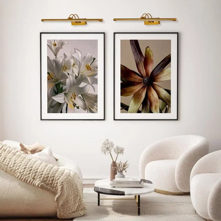 Gold metal picture lights highlighting framed artwork with focused illumination adding gallery inspired elegance to living spaces.