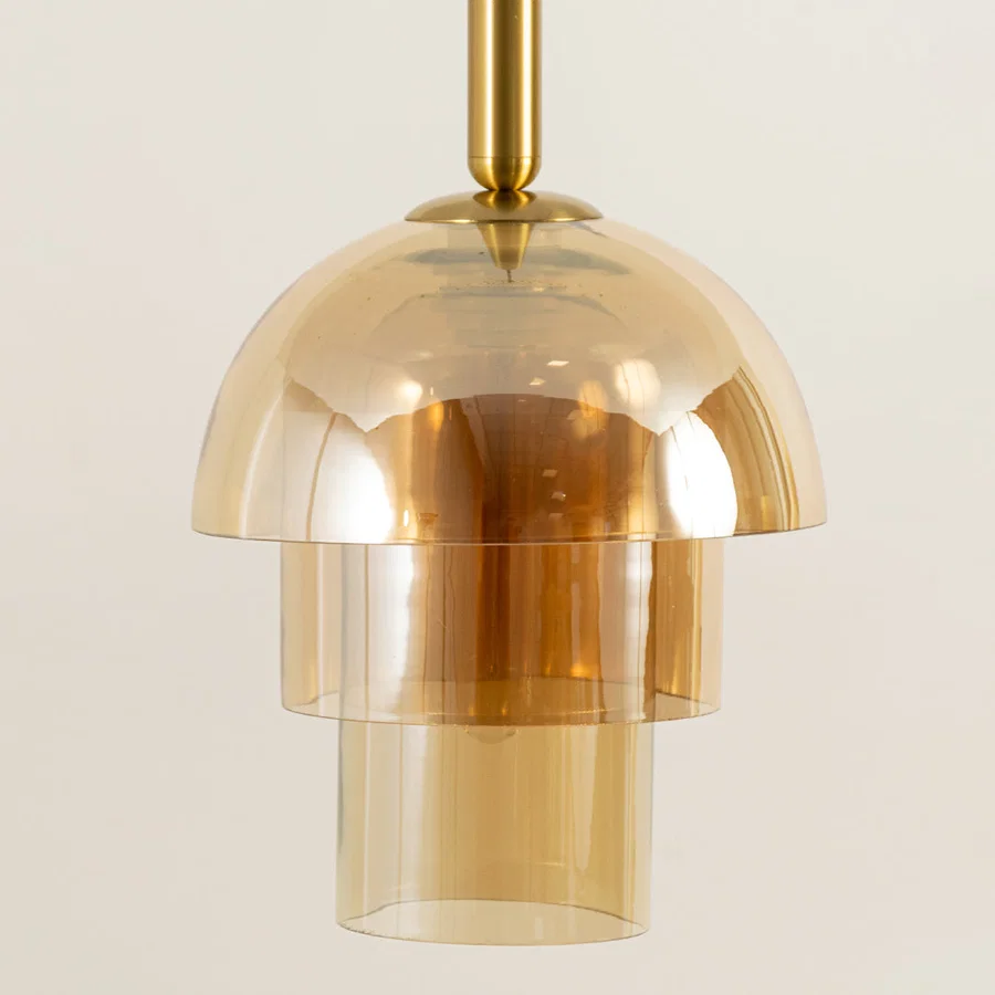 Closeup of amber glass pendant light with gold metal finish for elegant kitchen and dining room decor styling.