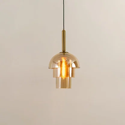 Gold metal pendant light with clear glass shade illuminated to highlight luxury decorative ceiling lighting appeal.