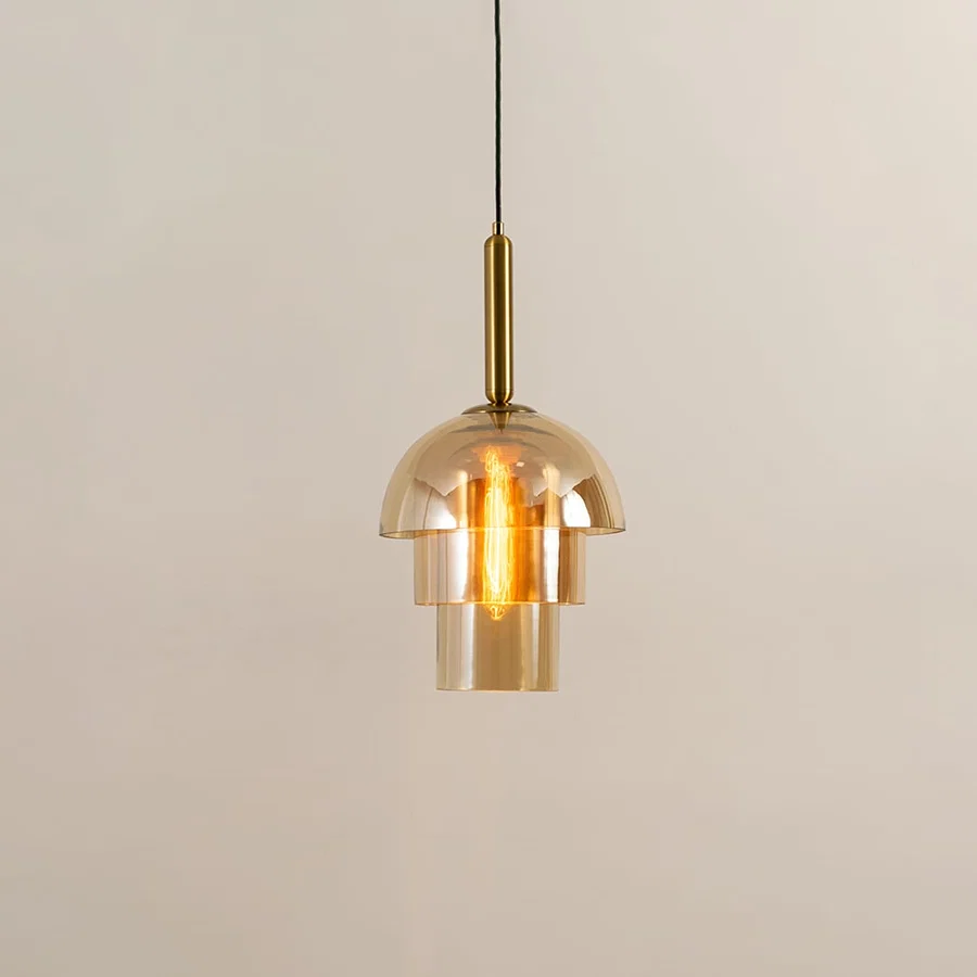 Gold metal pendant light with clear glass shade illuminated to highlight luxury decorative ceiling lighting appeal.
