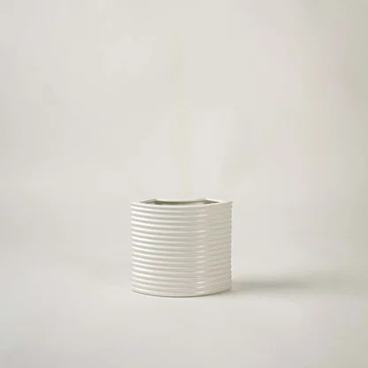 White ribbed ceramic decorative vase with textured finish for shelf styling and minimalist home decor displays.