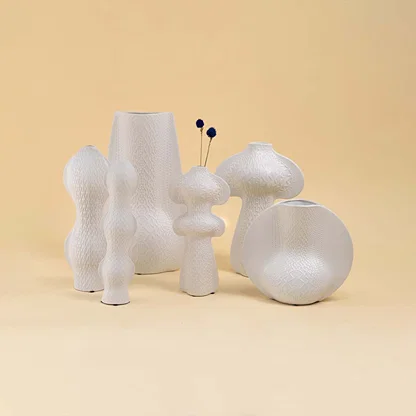 Set of white ceramic decorative vases with sculptural forms for elegant shelf styling and modern home decor.