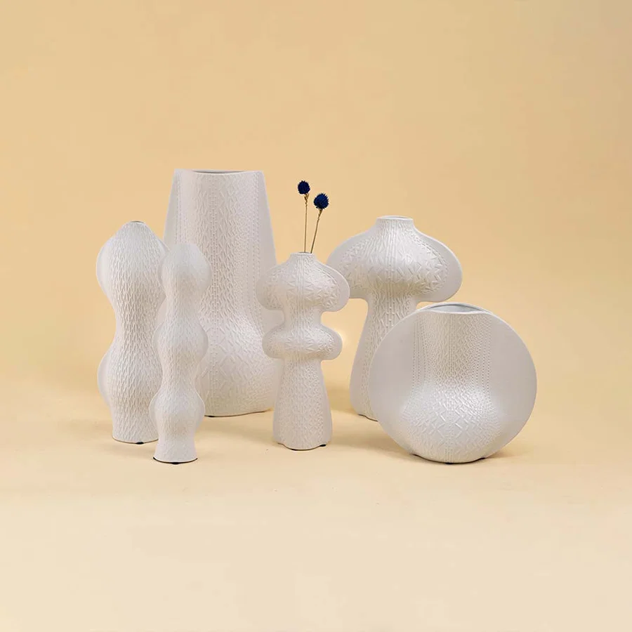 Set of white ceramic decorative vases with sculptural forms for elegant shelf styling and modern home decor.