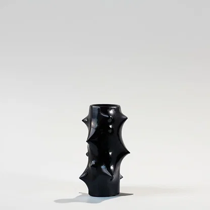 Black ceramic decorative vase with sculptural spike design for modern shelf styling and artistic home decor.