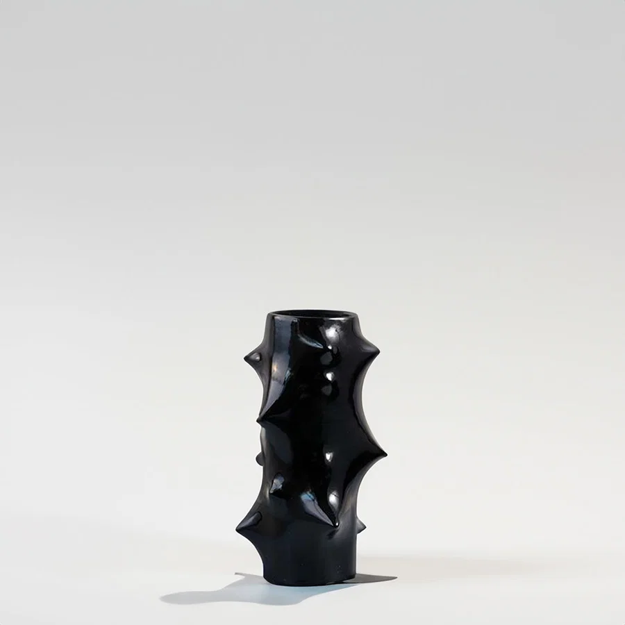 Black ceramic decorative vase with sculptural spike design for modern shelf styling and artistic home decor.