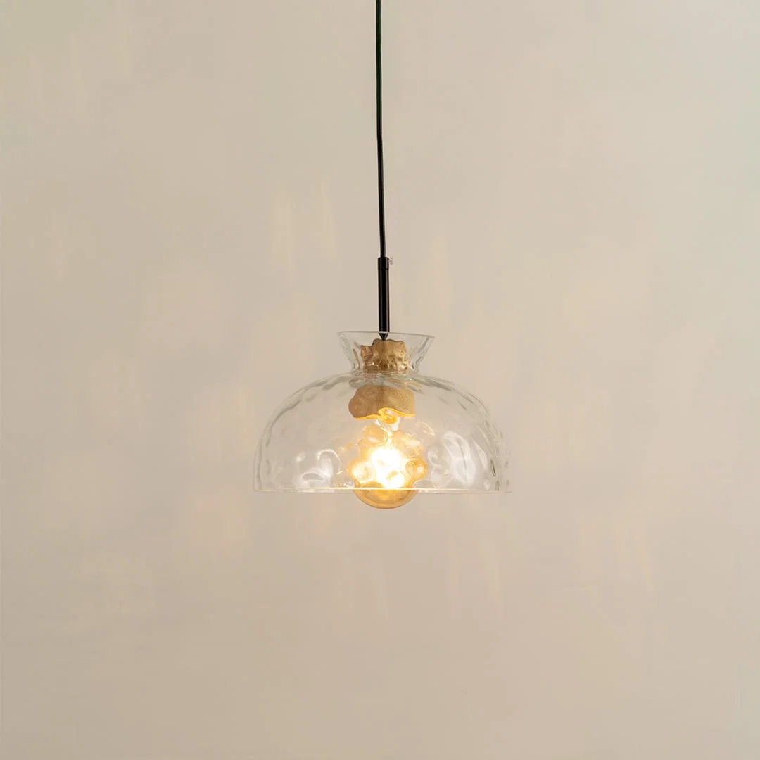 Clear sculpted glass and brass metal pendant light with warm glow for elegant modern interiors.