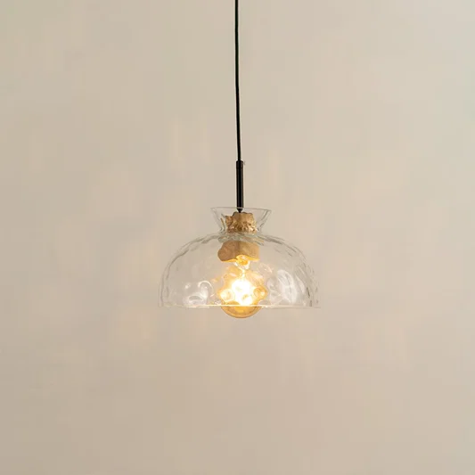 Clear sculpted glass and brass metal pendant light with warm glow for elegant modern interiors.