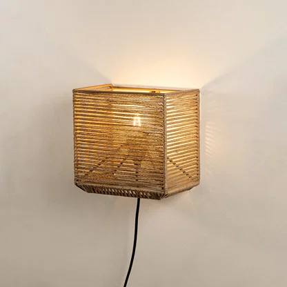 Wall light with woven natural fiber shade emitting warm glow ideal for cozy bedroom or living room wall decor placement.