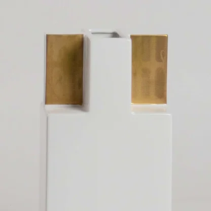 Closeup view of the white ceramic vase with gold top panels  showing its smooth finish  sharp structure  and elegant geometric form.