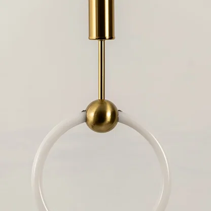 Gold metal ring pendant light creating warm ambient lighting above sofa in a modern living room setting.