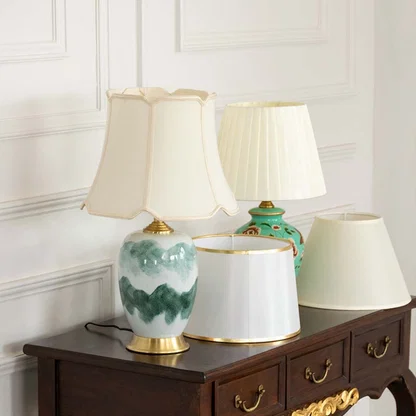 Table lamps light off with artistic ceramic bases and white shades placed on a dark wooden console for elegant home styling.