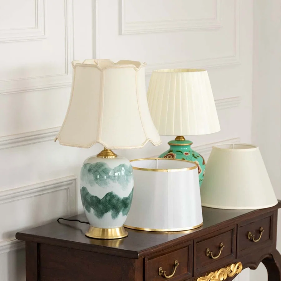 Table lamps light off with artistic ceramic bases and white shades placed on a dark wooden console for elegant home styling.
