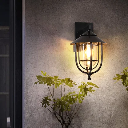 Black outdoor wall lantern styled in a minimal lifestyle setting showcasing its dome top clear glass shade and modern metal frame.