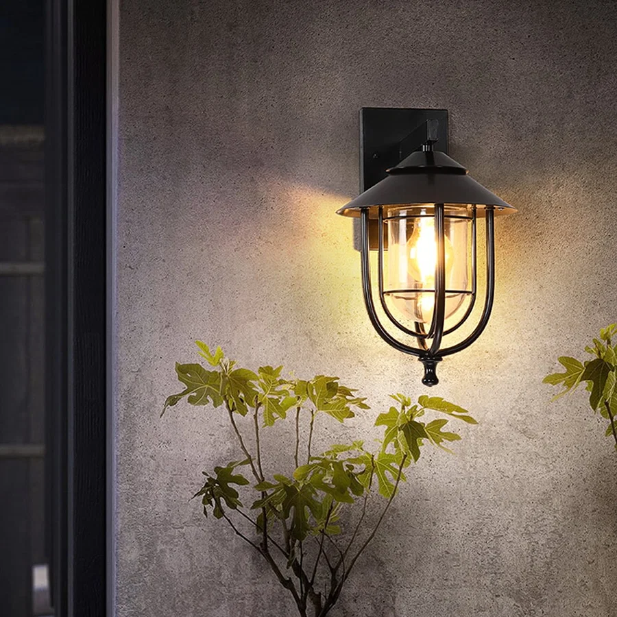 Black outdoor wall lantern styled in a minimal lifestyle setting showcasing its dome top clear glass shade and modern metal frame.