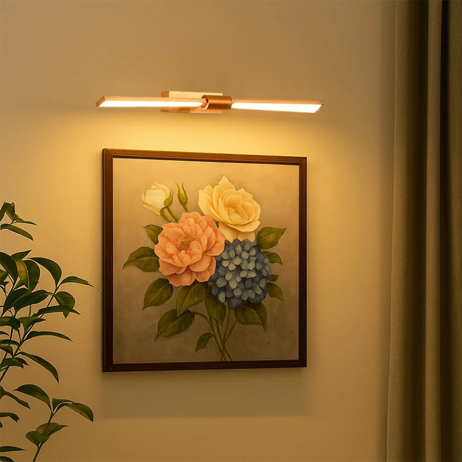 Gold metal picture light illuminating floral artwork with warm focused lighting creating elegant gallery style wall decor.