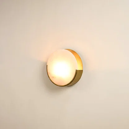Elegant marble wall sconce with golden base illuminated on white background showcasing timeless beauty perfect for modern and classic decor.