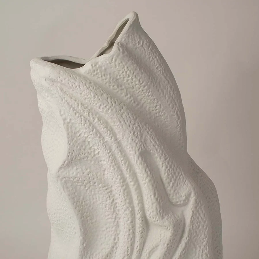White sculptural ceramic vase closeup highlighting flowing textured surface and handcrafted organic form for contemporary interior styling.