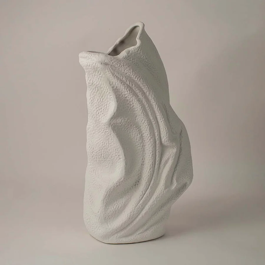 Side angle view of white ceramic decorative vase with sculptural wave texture ideal for living room or hallway decor.