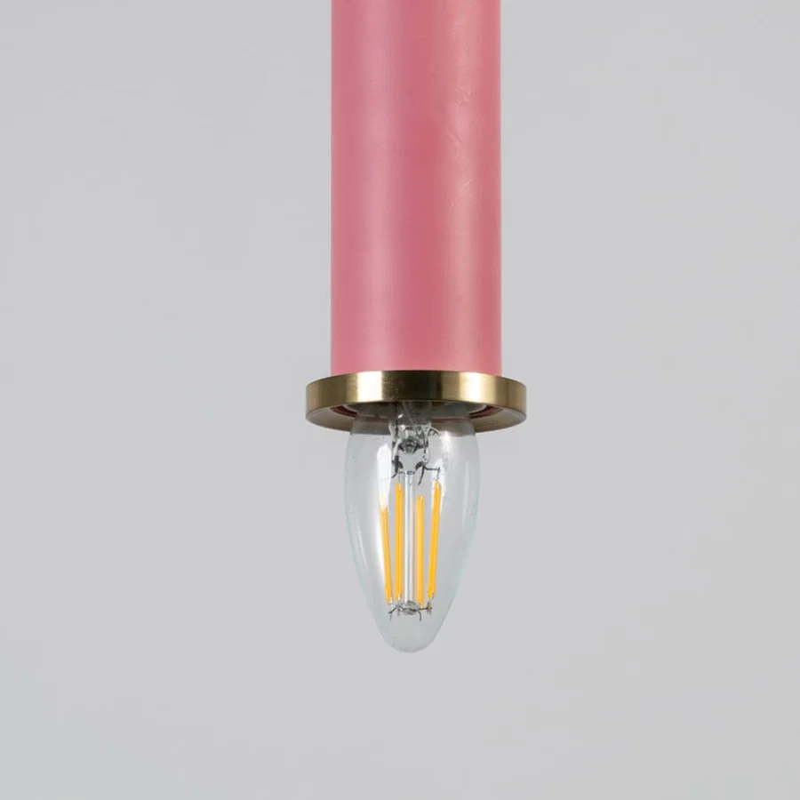 Pink metal pendant light with brass detailing showcasing sleek cylindrical form and modern Scandinavian style appeal.