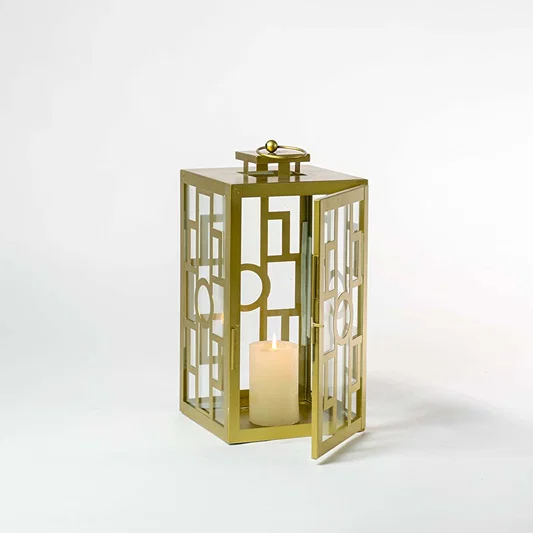 Gold metal lantern with geometric glass panels and candle holder for luxury tabletop decor styling.
