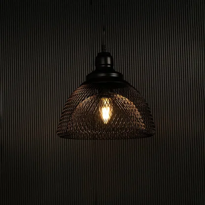 Elegant black mesh pendant light illuminated against dark background highlighting artistic industrial style and fine craftsmanship.
