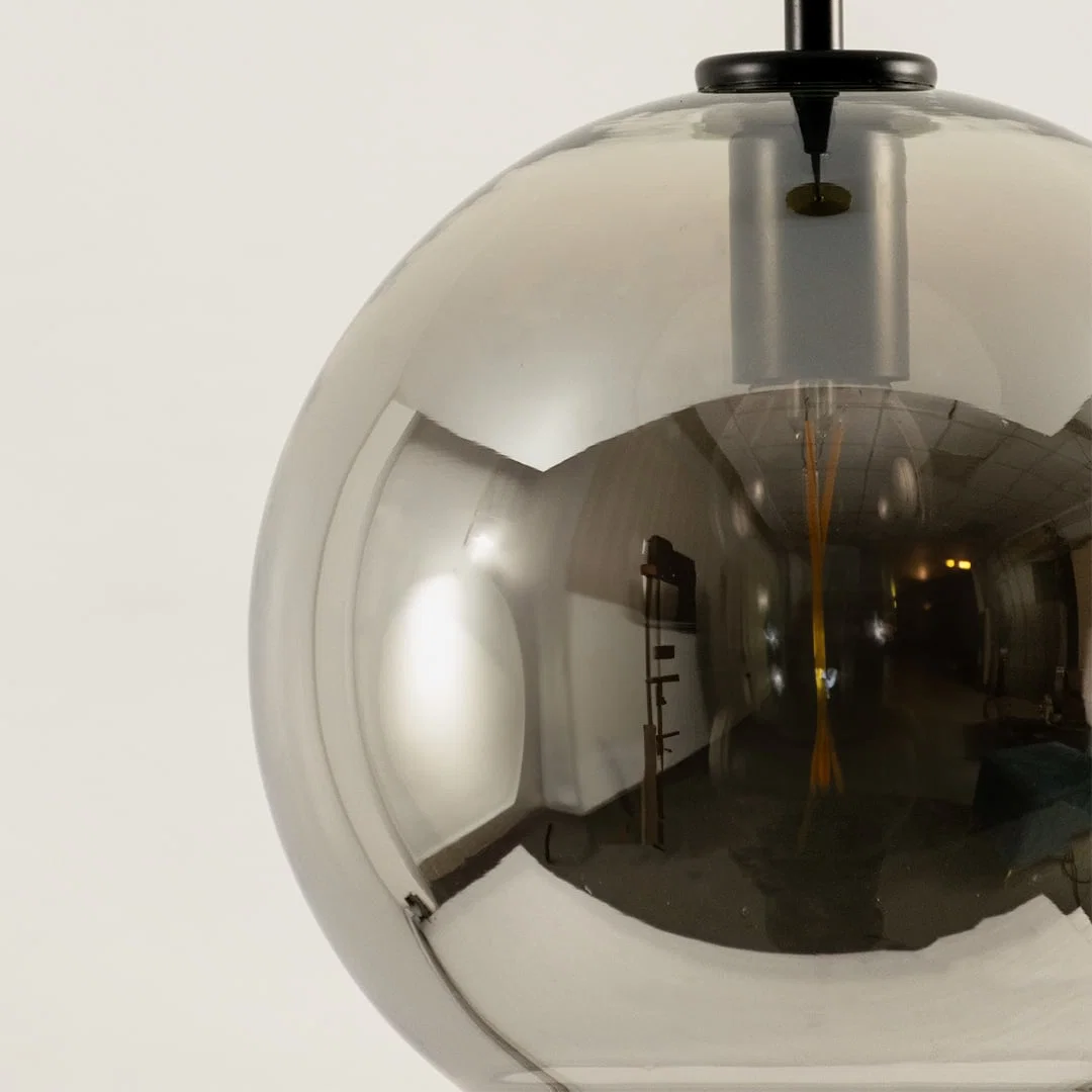 Detailed view of smoky glass globe pendant light with black cross accents and mirror finish.