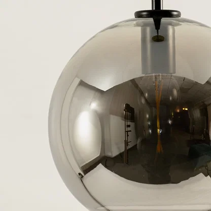 Detailed view of smoky glass globe pendant light with black cross accents and mirror finish.