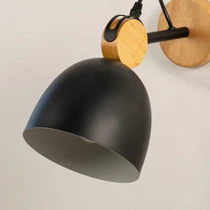 Closeup of black metal wall light with wooden backplate highlighting matte finish and design detail for modern interior wall decor.