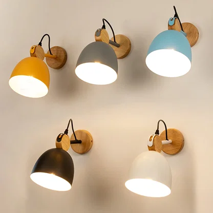 Five colorful dome wall lamps including yellow grey blue black and white variants casting warm light on a plain wall.