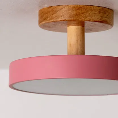 Closeup view of the ceiling light showing the natural wood texture and smooth pink shade with a neat modern finish.