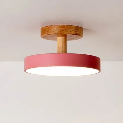 Closeup of red metal and natural wood flush mount ceiling light for Scandinavian decor and modern interior styling spaces.