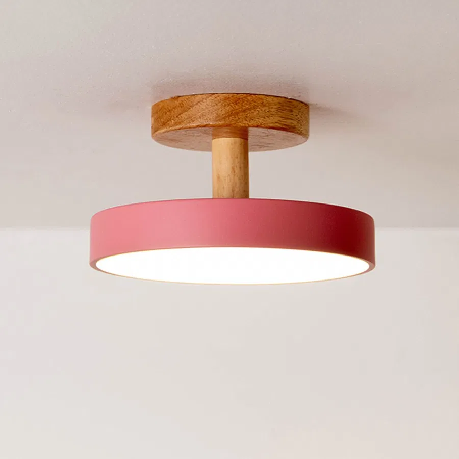 Closeup of red metal and natural wood flush mount ceiling light for Scandinavian decor and modern interior styling spaces.