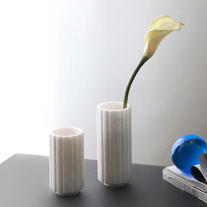 Set of two white marble vases with fluted design and glossy finish ideal for tabletop decoration and floral arrangements.