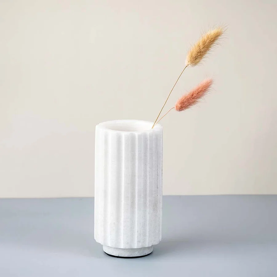 White marble vase with fluted design styled with dried stems ideal for modern living room table decor and floral arrangements.
