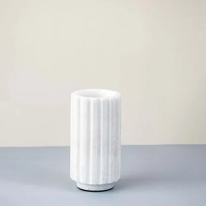 White ceramic decorative vase with vertical ribbed texture for shelf styling and contemporary home decor displays.