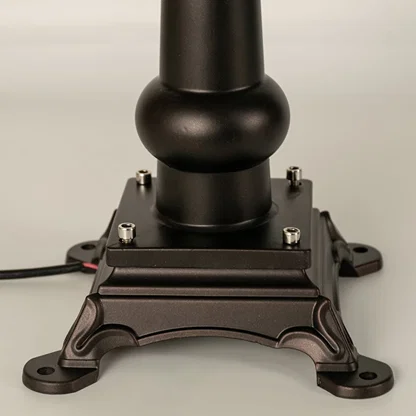 Closeup of a black outdoor pillar lamp showing glowing frosted glass and refined lantern edges designed for soft ambient garden and pathway lighting.