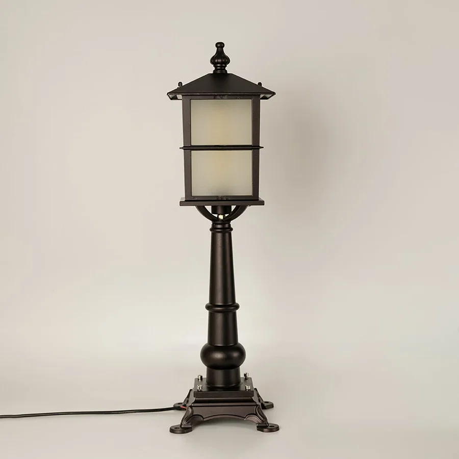 A black outdoor pillar lamp with frosted glass shown with light off on a white background emphasizing its clean lantern frame and ornate pillar detailing.