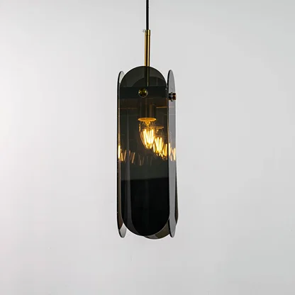 Grey glass pendant light displayed with light on against a dark background enhancing its warm illumination reflective finish and gold detailing.