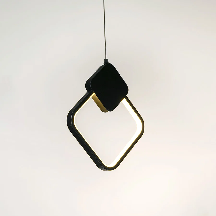 Black geometric pendant light with angular frame and hanging cord placed against neutral wall background highlighting modern artistic lighting design.