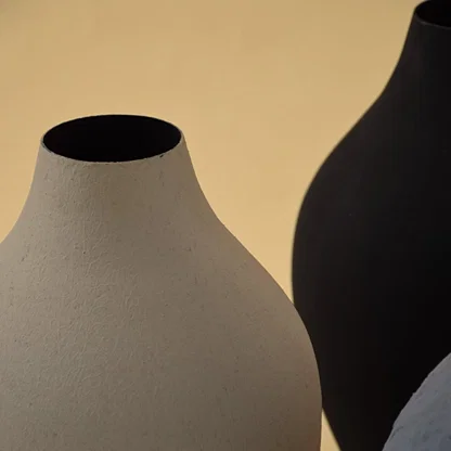 A detailed view of a sculpted textured vase highlighting its matte surface organic curves and handcrafted finish set against a soft warm toned background.