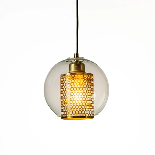 Contemporary round clear glass pendant lamp with exposed filament bulb and metal holder hanging against minimal neutral background ideal for modern interiors.