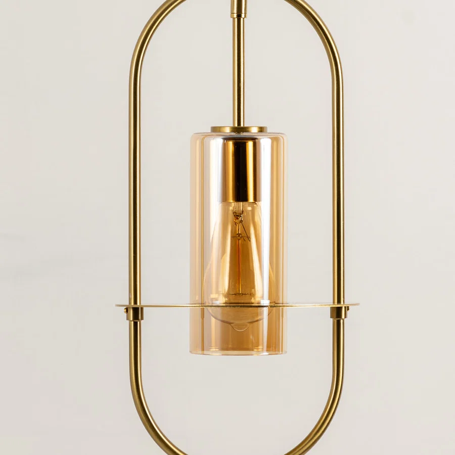 Closeup of gold metal pendant light with exposed bulb for elegant kitchen and dining room decor styling.