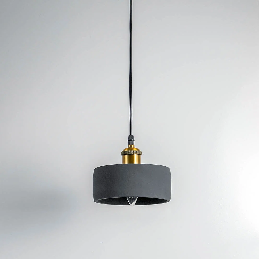Black metal pendant light with gold accents and flat drum shade crafted for modern living spaces.