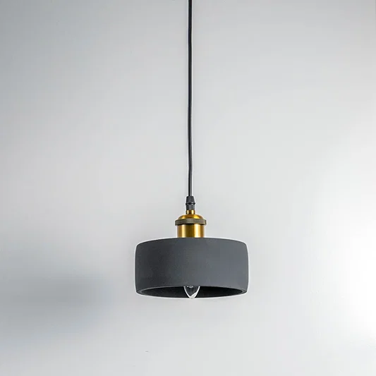 Black metal pendant light with gold accents and flat drum shade crafted for modern living spaces.