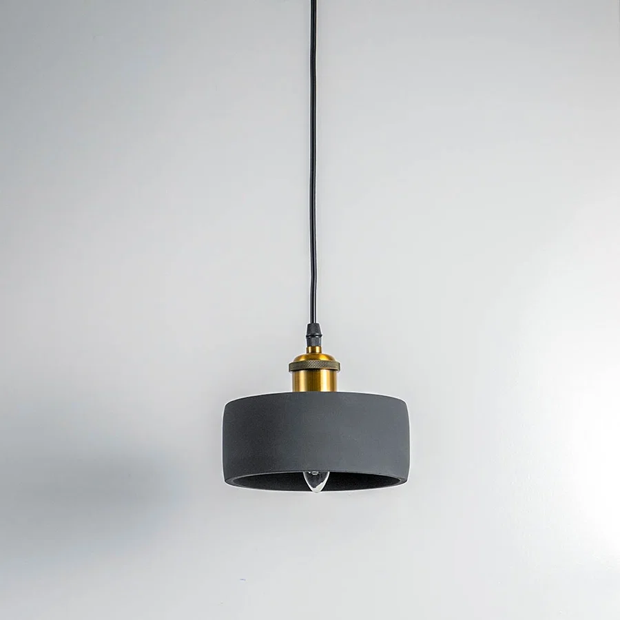 Black metal pendant light with gold accents and flat drum shade crafted for modern living spaces.