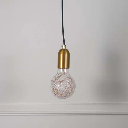 Decorative clear glass pendant light with brass accents and artistic wire detailing for stylish spaces.