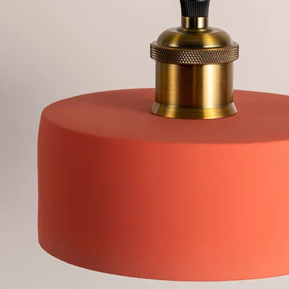 Closeup of terracotta orange metal pendant light with polished gold accents showcasing premium craftsmanship.