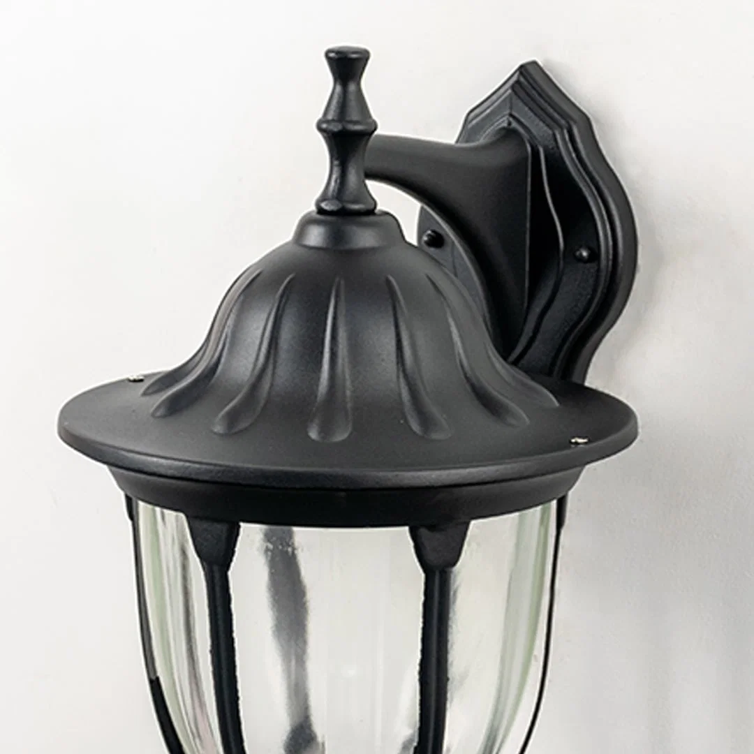 Closeup image of black metal outdoor wall light with textured top and ribbed glass for patio decor.