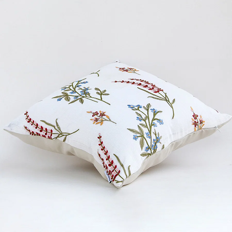 Floral embroidered cotton cushion displayed on a white background highlighting detailed stitched flowers and soft fabric texture ideal for home decor styling.