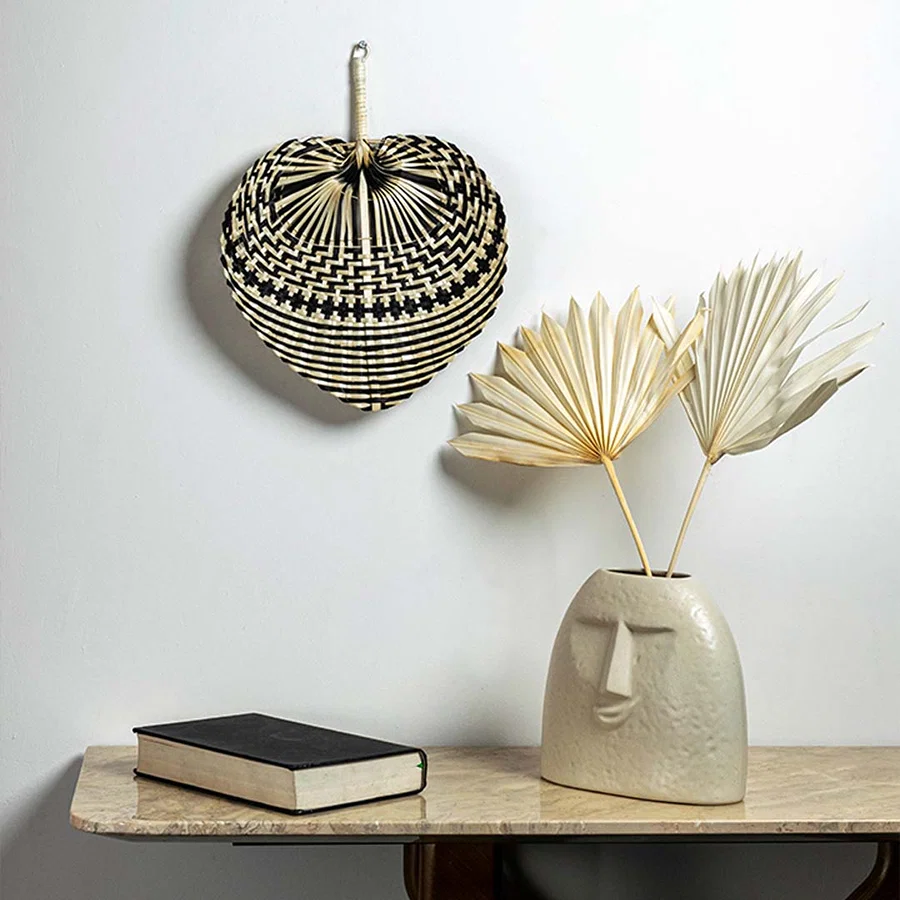 Black and natural woven bamboo hanging basket displayed in bohemian interior creating stylish handcrafted storage solution.Retry